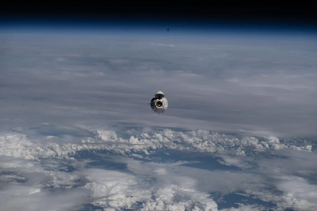 A Crew Dragon spacecraft approaches the International Space Station above Earth