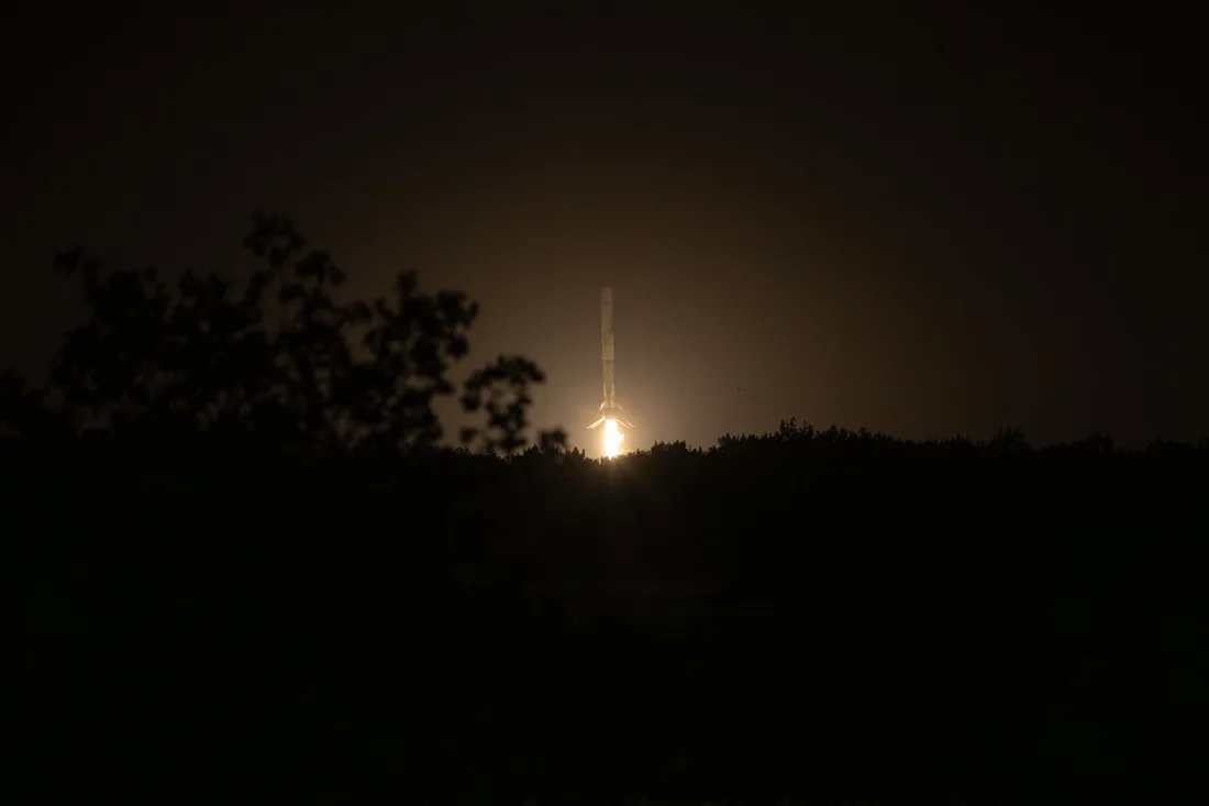 A Falcon 9 first-stage booster descends vertically on its landing burn